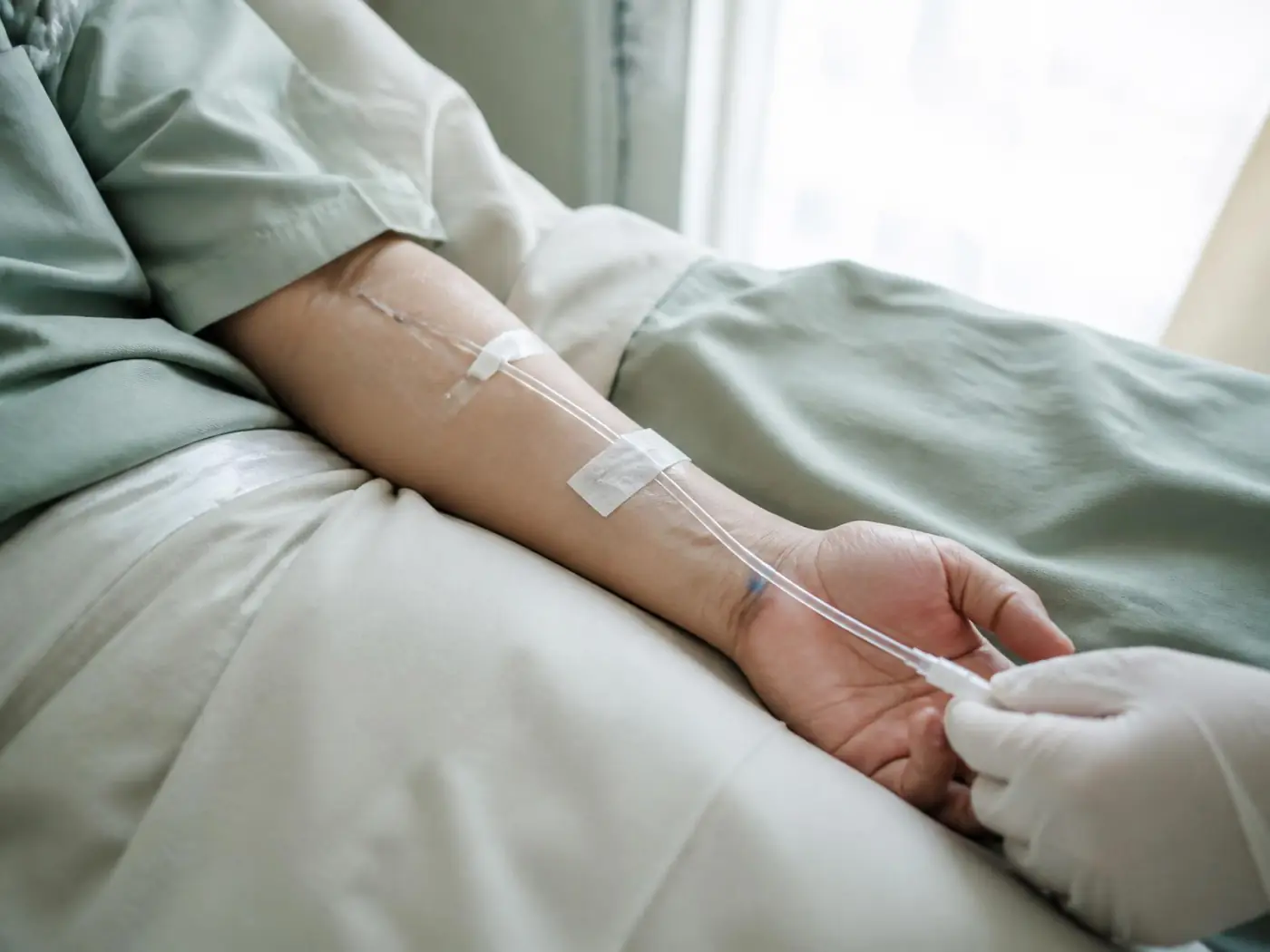 Clinician steadying an intravenous line secured to a patient's forearm